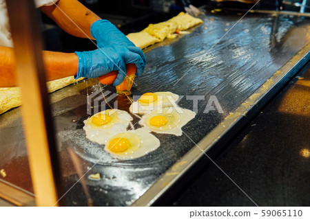 the Cook prepares the eggs in the kitchen of the restaurant the Cook prepares the eggs in the kitchen of the restaurant 59065110