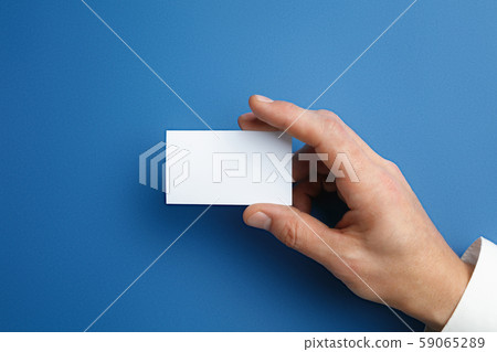 Male hand holding a blank business card on blue background for text or design 59065289