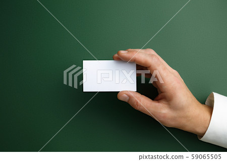 Male hand holding a blank business card on green background for text or design Male hand holding a blank business card on green background for text or design 59065505