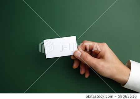 Male hand holding a blank business card on green background for text or design 59065516