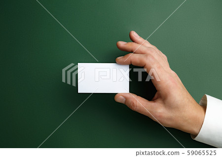 Male hand holding a blank business card on green background for text or design 59065525