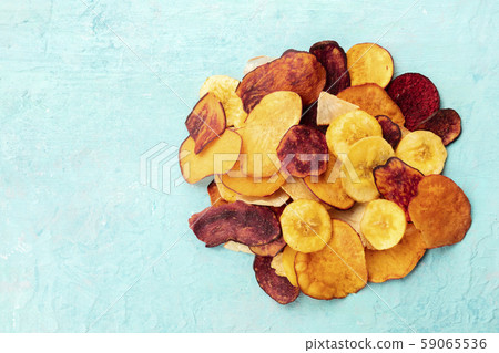 Dried fruit and vegetable chips, healthy vegan snack, a mixed heap on a blue background, overhead Dried fruit and vegetable chips, healthy vegan snack, a mixed heap on a blue background, overhead 59065536