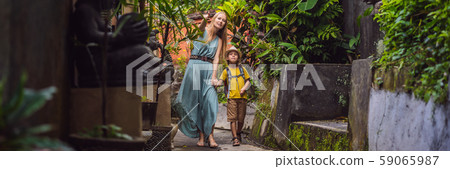 Mother and son tourists in Bali walks along the narrow cozy streets of Ubud. Bali is a popular Mother and son tourists in Bali walks along the narrow cozy streets of Ubud. Bali is a popular 59065987