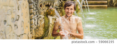 Young man in hot springs banjar. Thermal water is released from the mouth of statues at a hot 59066195