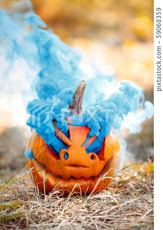 Halloween Preparaton Concept. Carved pumpkin with colored gas on ground close-up 59068359