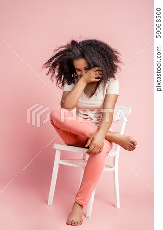 Freestyle. African girl sitting on chair isolated on pink covering face laughing happy Freestyle. African girl sitting on chair isolated on pink covering face laughing happy 59068500