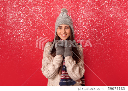 Freestyle. Young woman wearing scarf and hat standing isolated on red making heart with hands 59073183