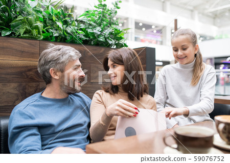 Young woman with paperbag and her husband discussing purchase in cafe Young woman with paperbag and her husband discussing purchase in cafe 59076752