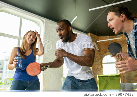 Young people playing table tennis in workplace, having fun Young people playing table tennis in workplace, having fun 59077432