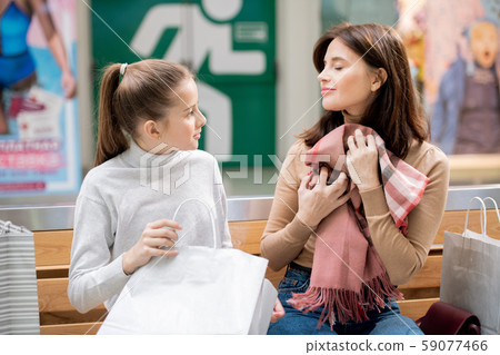 Pleased woman holding new cashmere scarf by chest while girl looking at mother Pleased woman holding new cashmere scarf by chest while girl looking at mother 59077466