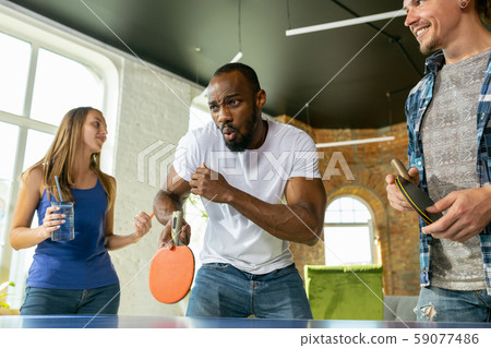 Young people playing table tennis in workplace, having fun Young people playing table tennis in workplace, having fun 59077486