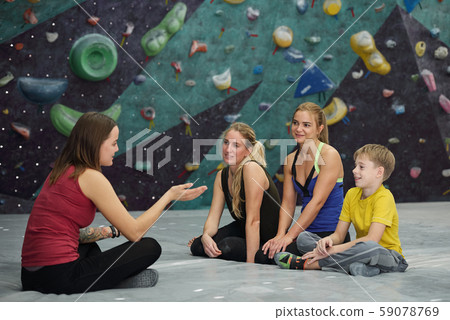 Climbing instructor with crossed legs sitting in front of three trainees 59078769