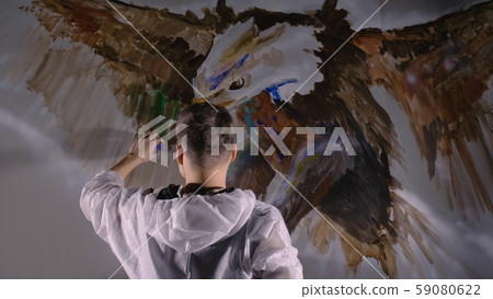 Artist designer draws an eagle on the wall. Craftsman decorator paints picture with acrylic oil 59080622