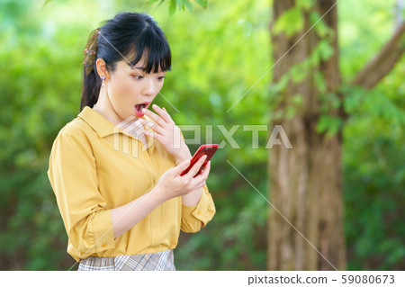 A woman surprised to see a smartphone 59080673