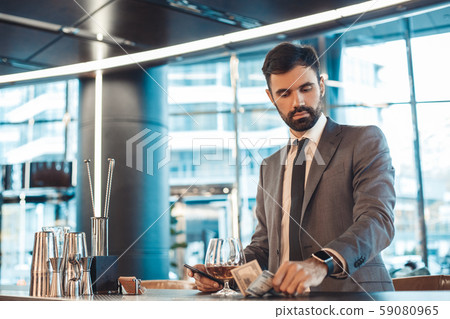 Businessman standing at a business center bar counter paying bill 59080965