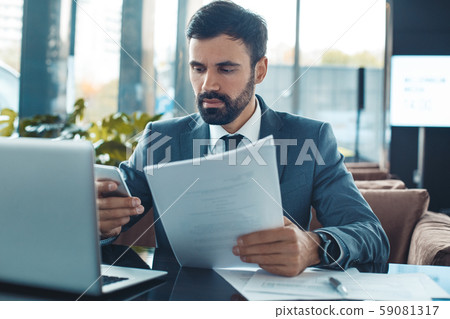 Businessman sitting in a business center restaurant reading contract calling front view Businessman sitting in a business center restaurant reading contract calling front view 59081317