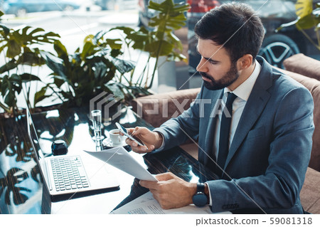 Businessman sitting in a business center restaurant reading contract calling side view Businessman sitting in a business center restaurant reading contract calling side view 59081318