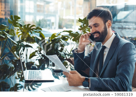 Businessman sitting in a business center restaurant answering phone reading contract 59081319
