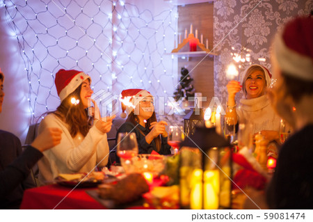 Beautiful young mother looking at her hand fireworks during christmas celebration with her family Beautiful young mother looking at her hand fireworks during christmas celebration with her family 59081474