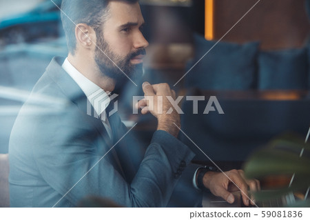 Businessman sitting in a business center restaurant with laptop thoughtful 59081836