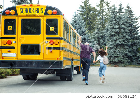 Being Late. Father and daughter following school bus back view waving to driver Being Late. Father and daughter following school bus back view waving to driver 59082124