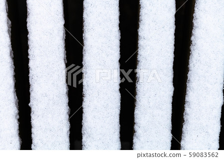 the first snow on bars of wooden bench outdoors 59083562