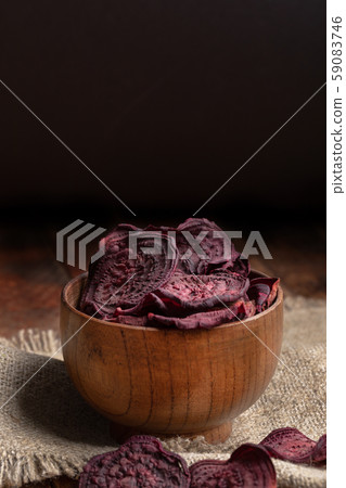 Homemade beetroot chips in wooden bowl on burlap on old wooden table on dark background. Natural healthy vegetable snack. Alternative to ready-made chips. Copy space. Homemade beetroot chips in wooden bowl on burlap on old wooden table on dark background. Natural healthy vegetable snack. Alternative to ready-made chips. Copy space. 59083746