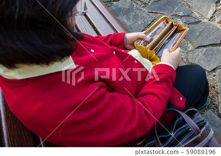 一名老婦檢查她的錢包的內容 一名老婦檢查她的錢包的內容 59089196