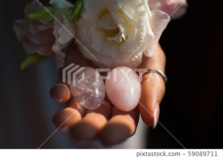 Female hands holding two yoni eggs for vumfit, imbuilding or meditation are made from pink quartz 59089711