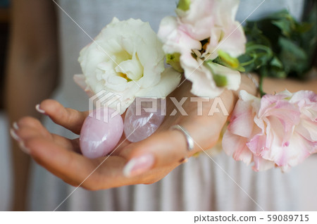Female hands holding two yoni eggs for vumfit, imbuilding or meditation are made from pink quartz 59089715