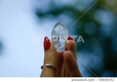 Female hand with transparent amethyst quartz yoni egg for vumfit, imbuilding or meditation. Shining 59089742