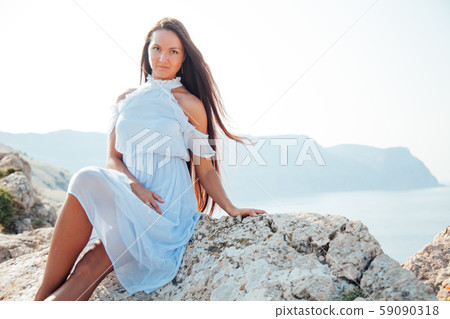 A beautiful woman with long hair in a dress looks at the landscape A beautiful woman with long hair in a dress looks at the landscape 59090318