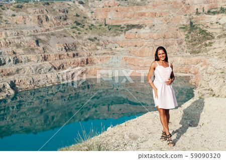 Beautiful woman with long hair in dress looks at the landscape of the lake Beautiful woman with long hair in dress looks at the landscape of the lake 59090320