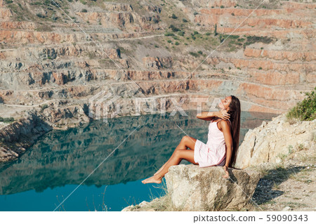Beautiful woman with long hair in dress looks at the landscape of the lake Beautiful woman with long hair in dress looks at the landscape of the lake 59090343