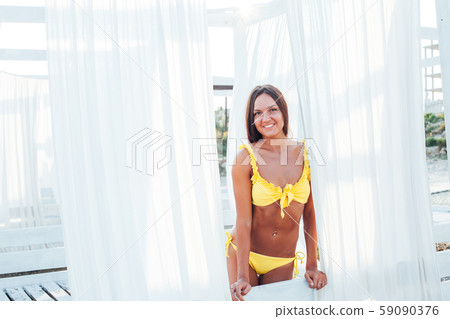 beautiful tanned woman with long hair in yellow swimsuit on the beach by the sea beautiful tanned woman with long hair in yellow swimsuit on the beach by the sea 59090376