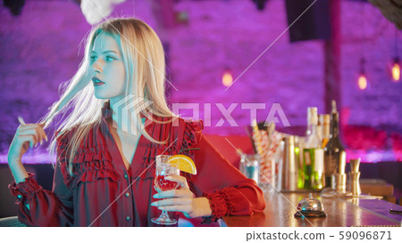 Gorgeous blonde young woman with red lipstick sitting by the bartender stand and playing with her Gorgeous blonde young woman with red lipstick sitting by the bartender stand and playing with her 59096871