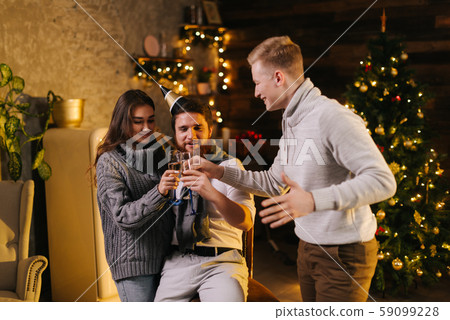 Cheerful man clinking champagne glasses with couple in celebrating new year Cheerful man clinking champagne glasses with couple in celebrating new year 59099228