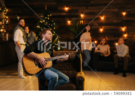 Handsome cheerful man plays guitar and sings in front of friends 59099381