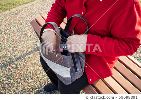 An elderly woman exploring the contents of a bag An elderly woman exploring the contents of a bag 59099891