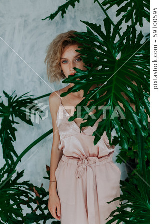 Portrait of a beautiful fashionable blonde woman at a green plant 59100595