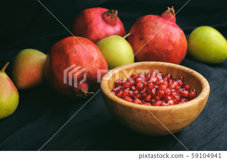 pomegranates and pears on a dark background and a Cup of peeled grains pomegranates and pears on a dark background and a Cup of peeled grains 59104941