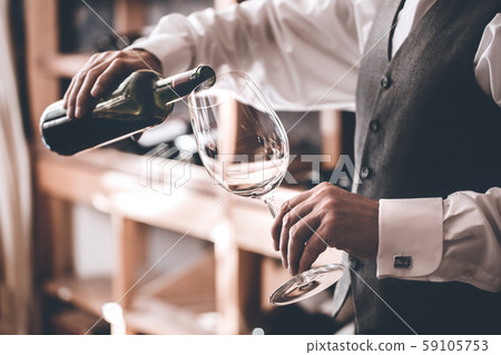 Sommelier Concept. Senior man standing pouring wine into glass close-up Sommelier Concept. Senior man standing pouring wine into glass close-up 59105753
