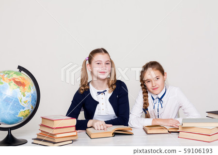 two schoolgirl girls at the desk in a geography class two schoolgirl girls at the desk in a geography class 59106193