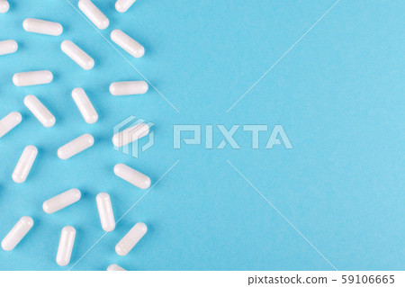 white medicine capsules on blue background with copy space 59106665