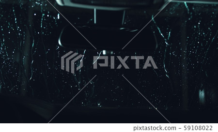Drops flow down the windscreen. Inside view of a windshield car. Dark black cinematic picture 59108022