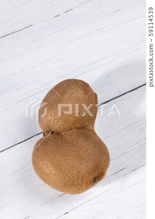 Single non-standard deformed conjoined ugly kiwi on white painted wooden table with copy space. Waste zero concept. Top view, copy space. Single non-standard deformed conjoined ugly kiwi on white painted wooden table with copy space. Waste zero concept. Top view, copy space. 59114539