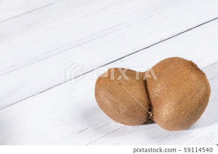 One non-standard deformed conjoined ugly kiwi on diagonal white painted wooden table. Top view, copy space. Waste zero concept. Image with copy space. One non-standard deformed conjoined ugly kiwi on diagonal white painted wooden table. Top view, copy space. Waste zero concept. Image with copy space. 59114540