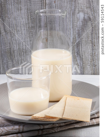 Close-up dairy free oat milk in glass bottle and glass in grey plate on grey wooden background. Lactose free milk concept. Image with copy space. Close-up dairy free oat milk in glass bottle and glass in grey plate on grey wooden background. Lactose free milk concept. Image with copy space. 59114543