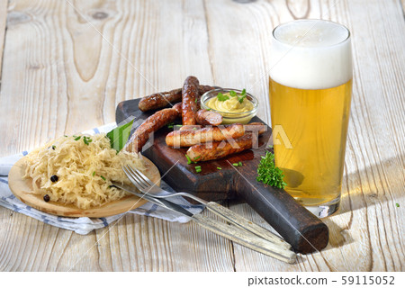 Fried Bavarian sausages from Nuremberg served with sauerkraut and a lager beer 59115052