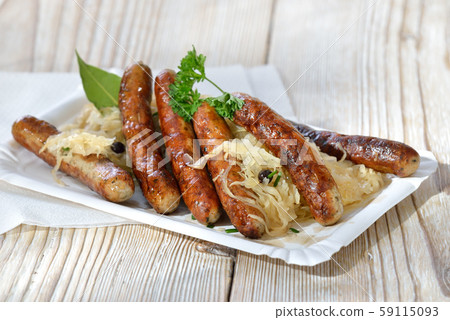Six fried Bavarian sausages from Nuremberg served with sauerkraut on a paper plate 59115093